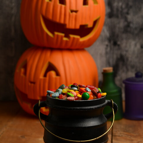 Halloween candy in black cauldron with pumpkins in background